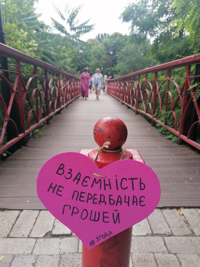 Жінка прикрашає Міст кохання, Київ, 28 червня 2021 року. Флешмоб про згоду на секс до 25-ї річниці Конституції України
